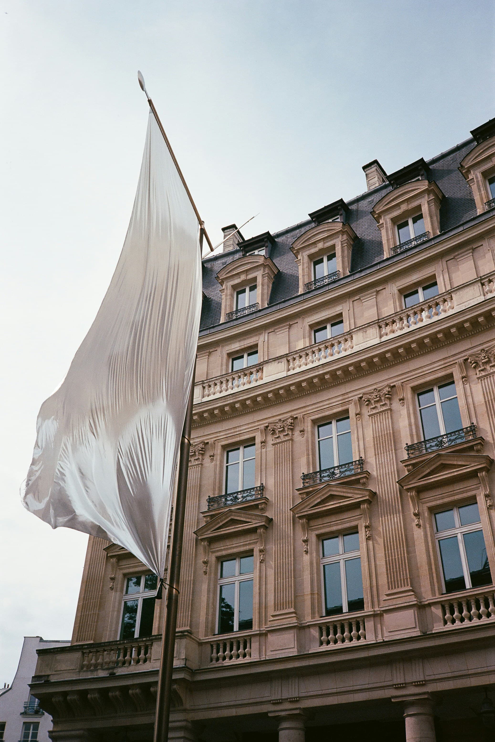 A large white flag hangs beside an ornate stone building